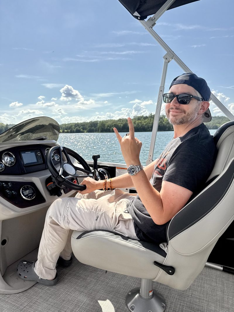 Eli at the helm of his pontoon on Watts Bar Lake, mid-channel on a sunny afternoon.